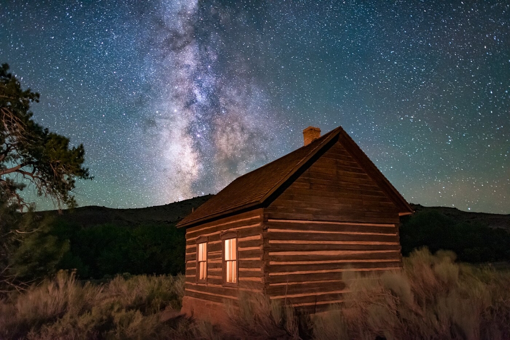 The Fruita Schoolhouse illuminated under the celestial grandeur of the Milky Way. Situated in Fruita, Utah, within Capitol Reef National Park, this single-room structure served as a place of learning for the small local community in the early 20th century.