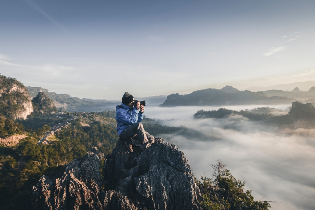 Photographer sitting above the clouds on a mountain